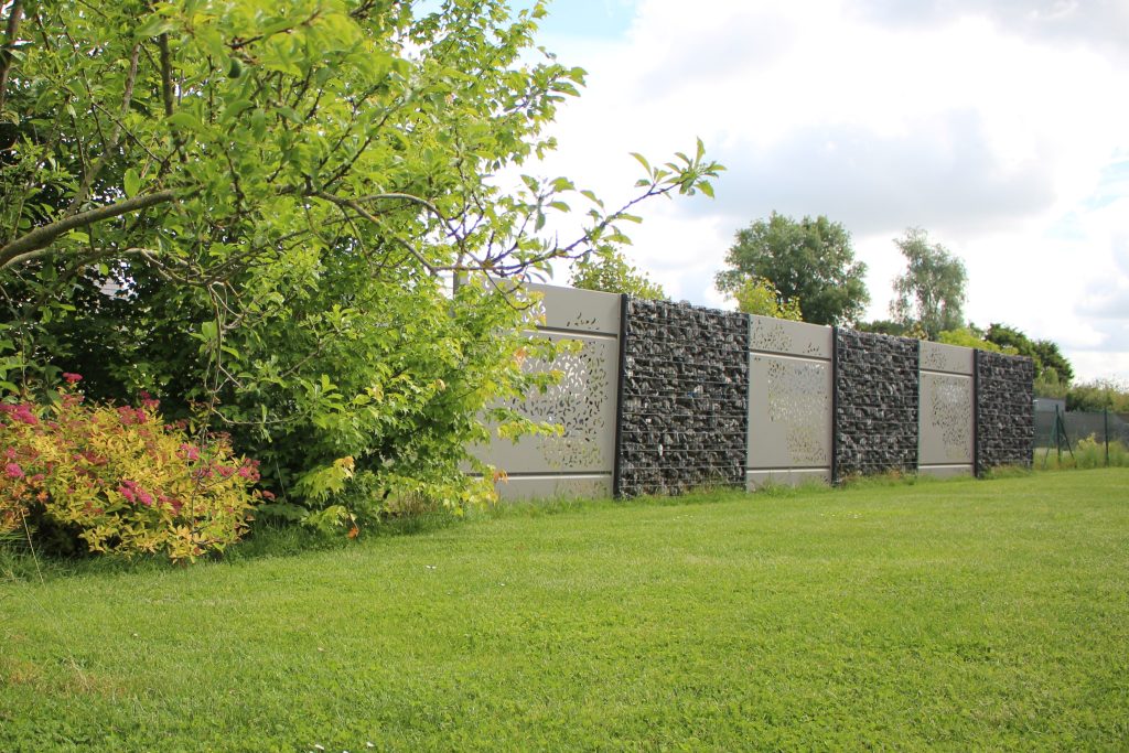 Dans un jardin, brises-vue modernes composés de panneaux en aluminium avec de fins motifs découpés au laser, et des panneaux de gabions remplis de roches noires.
